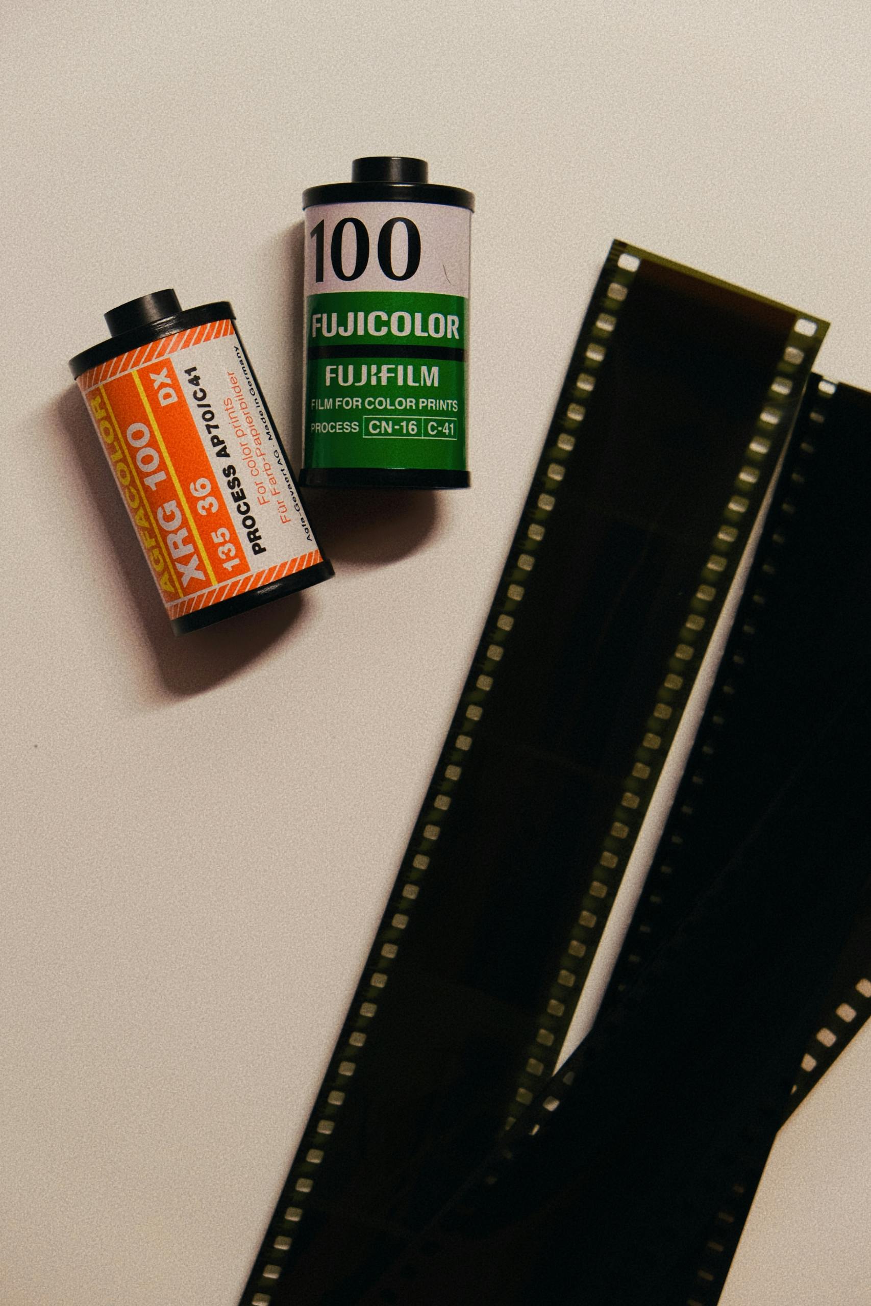 Two photographic film rolls next to exposed film strips on a white background.