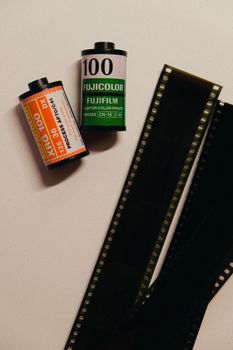 Two photographic film rolls next to exposed film strips on a white background.