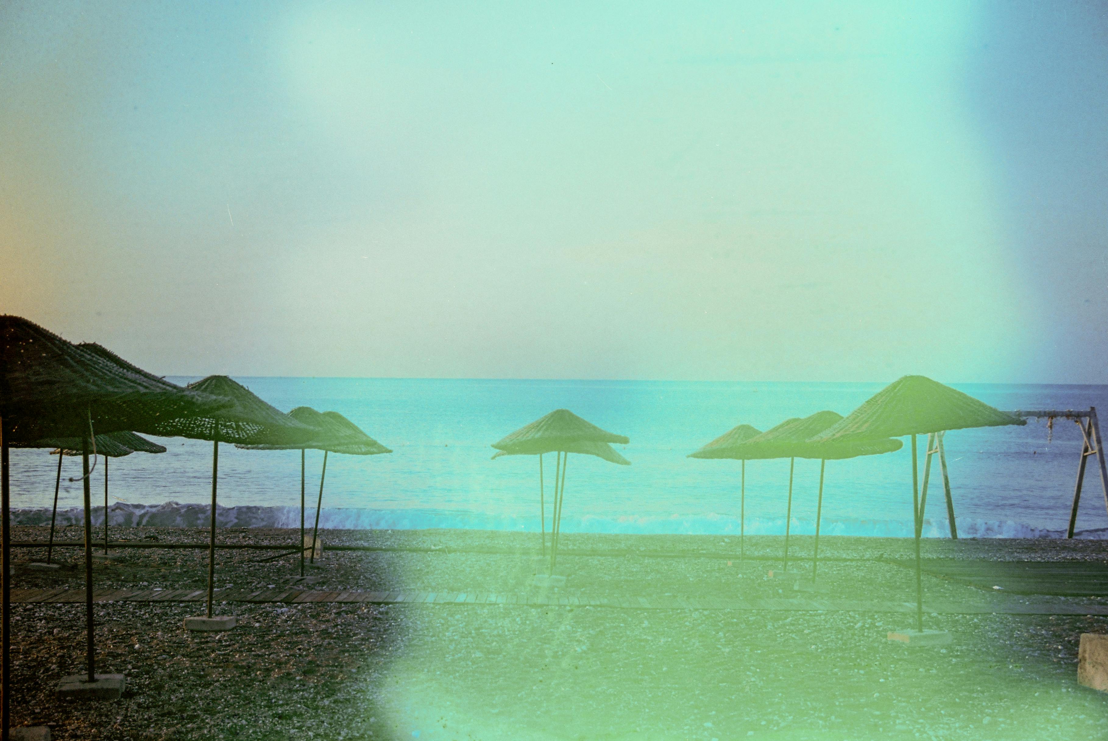 Tranquil beach scene with straw umbrellas and a vibrant sea horizon. Perfect vacation spot.