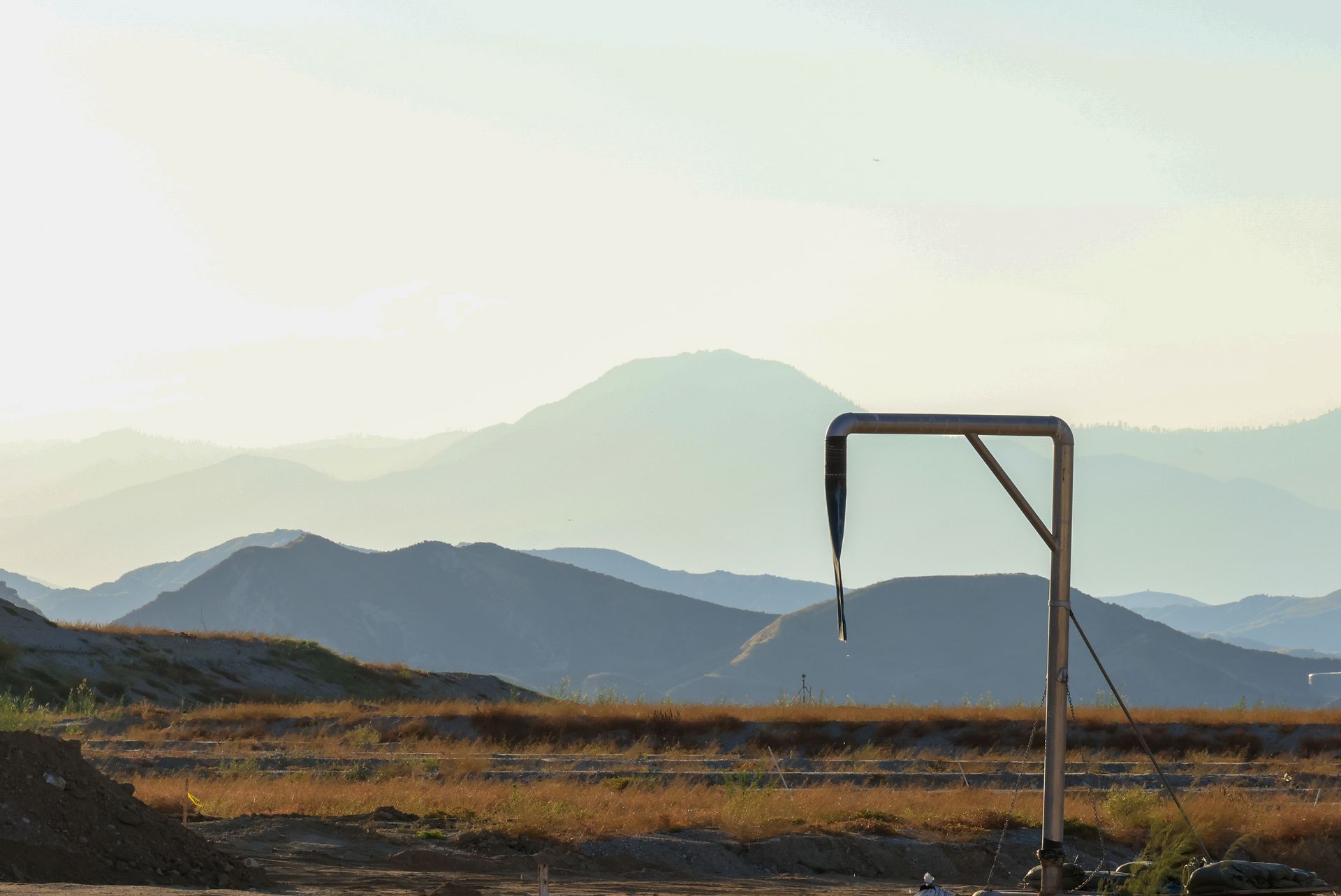 A serene mountain landscape featuring a metal pipeline structure under soft sunlight.