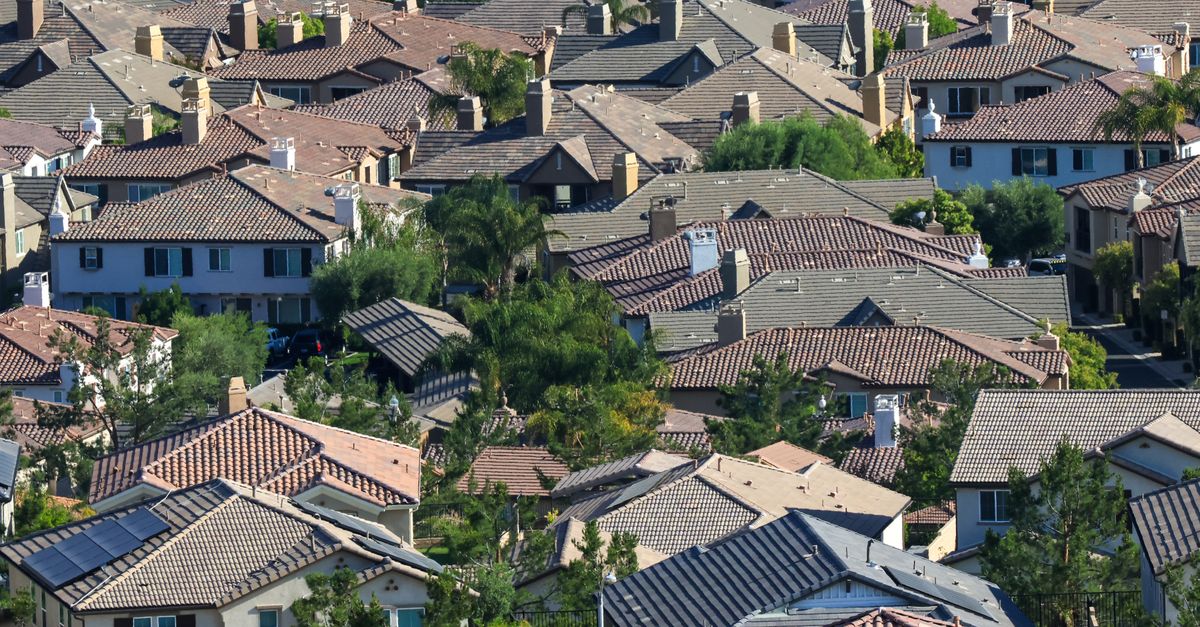 Luftaufnahme von Hausdächern eines Wohngebiets im Sonnenlicht