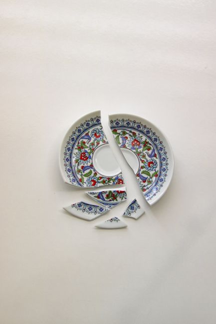Broken floral-patterned plate arranged on a white background in a studio setting.