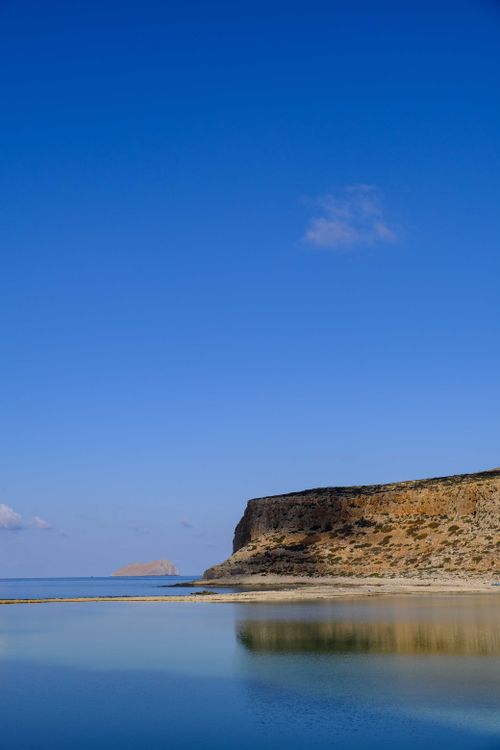 Free A tranquil coastal scene featuring a rugged cliff and blue ocean under a clear sky, ideal for travel and nature themes. Stock Photo