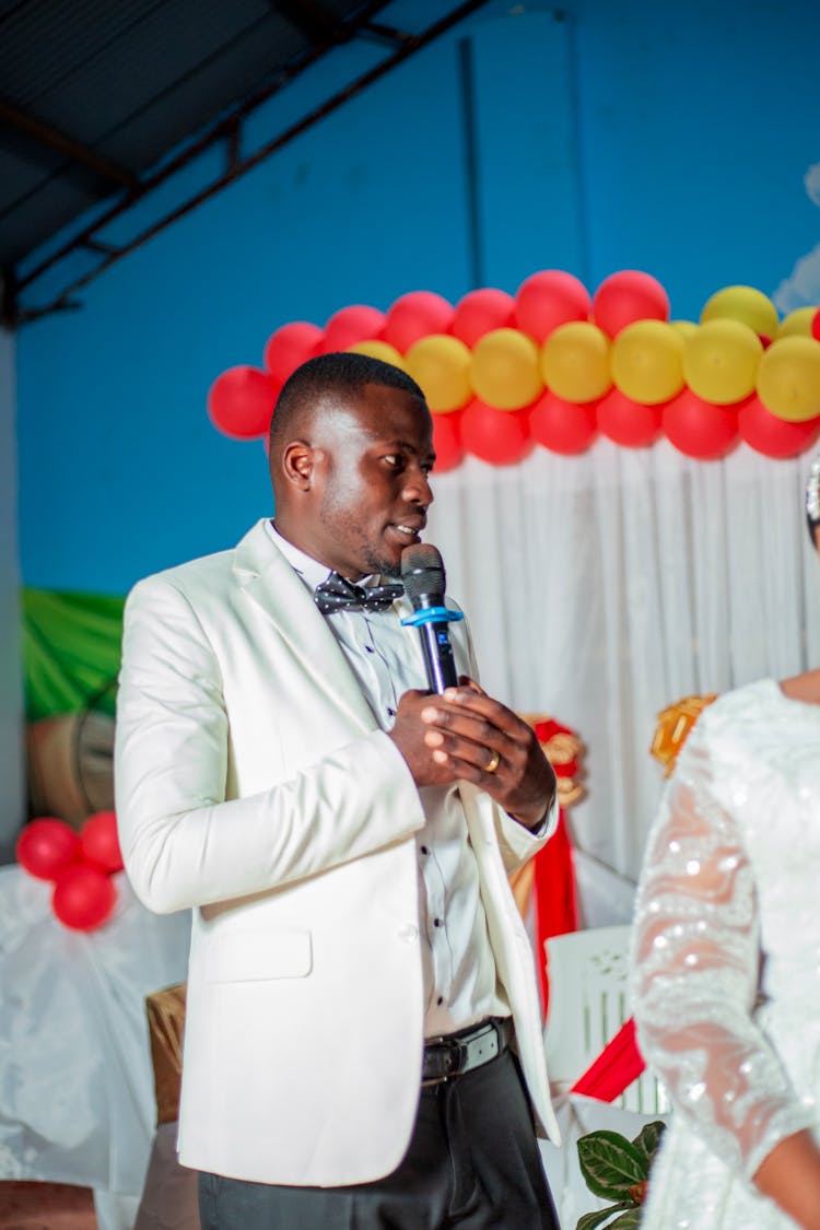 Man In White Suit Speaking On Ceremony