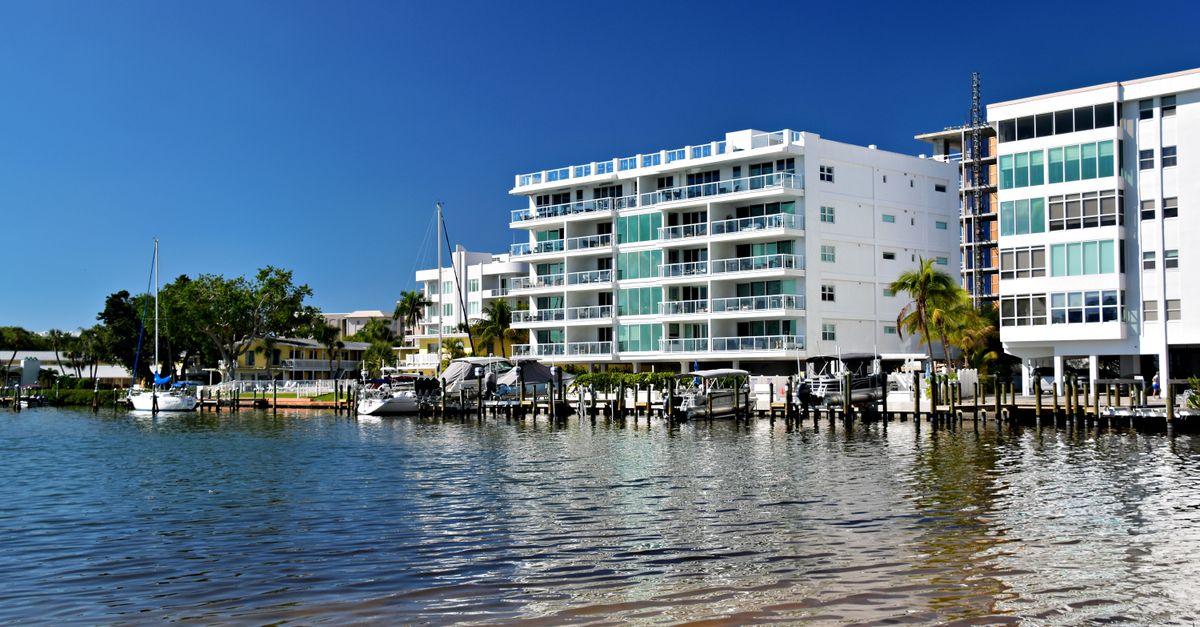 Charming waterfront apartments reflecting in calm water on a sunny day.
