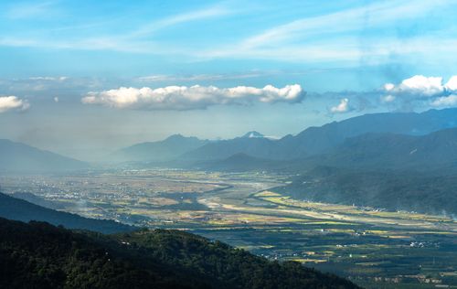 Free Drone view of expansive fields surrounded by mountains under a clear blue sky. Stock Photo