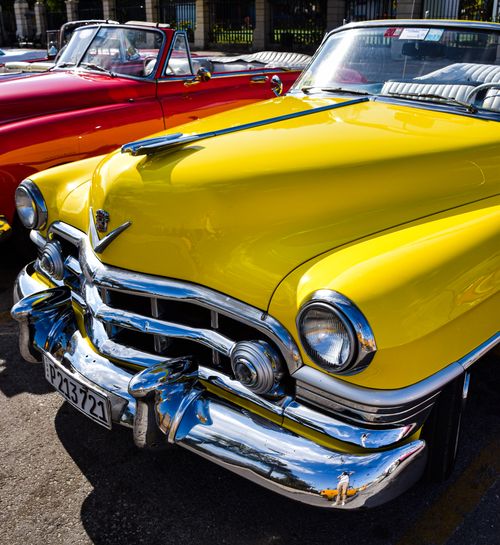 Free A classic yellow cabriolet displayed outdoors with sunlight highlighting its vintage design. Stock Photo