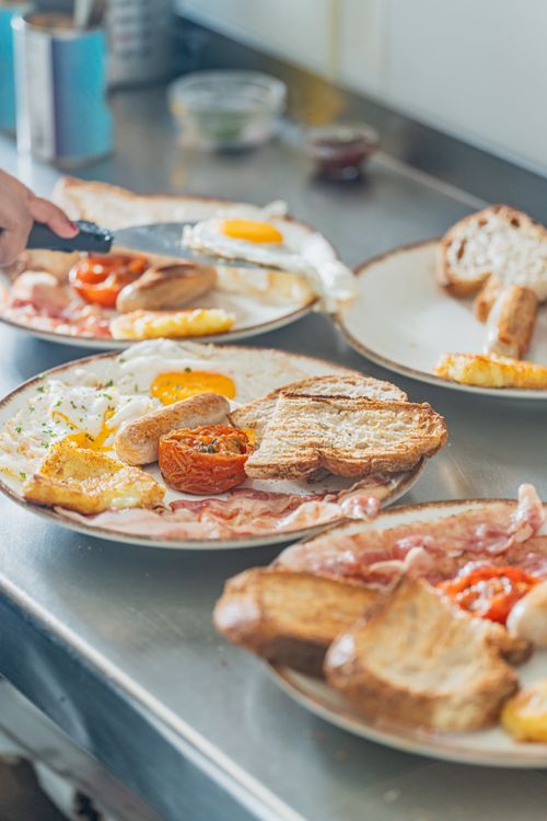 Free Savor a traditional English breakfast featuring eggs, bacon, sausages, and toast on a counter. Stock Photo