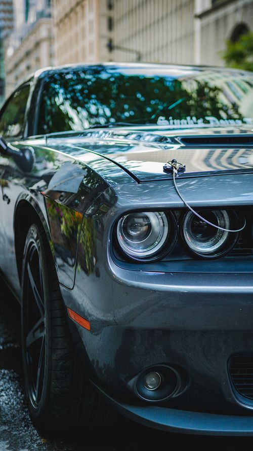 Free A stylish black sports car reflecting city lights, parked on an urban street, showcasing luxury and design. Stock Photo