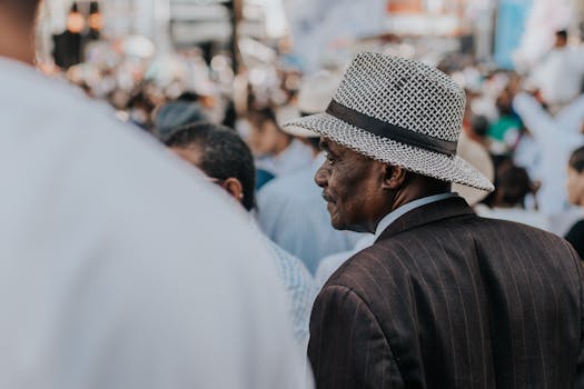 一名戴着编织帽的男子站在街头人群中，捕捉着城市生活的多样性