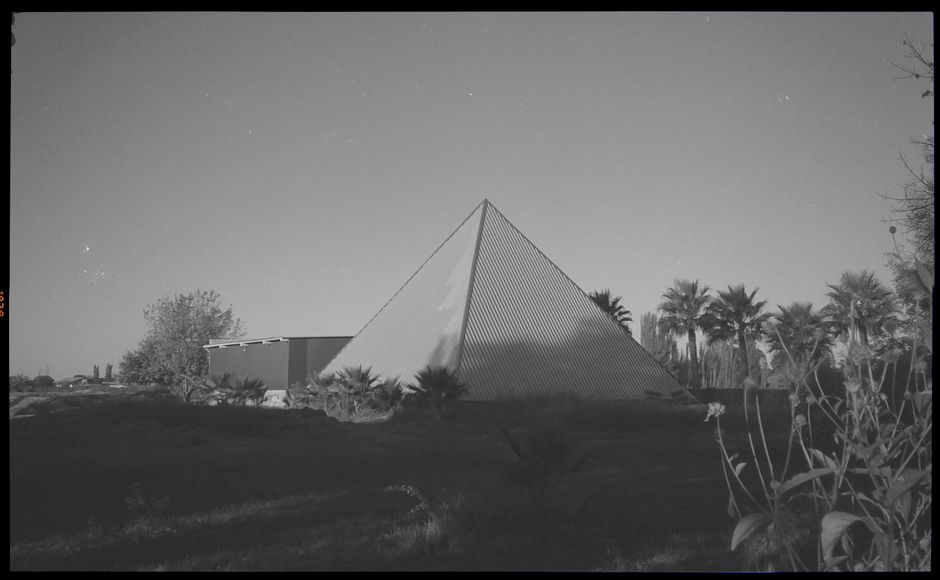 A striking modern pyramid amidst palm trees at sunset, located in Mendoza, Argentina.