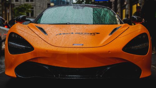 Free Front view of a McLaren 720S with raindrops in an urban setting, showcasing luxury car design. Stock Photo