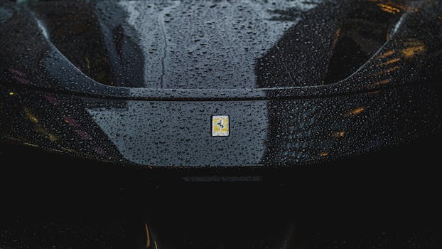 Close-up of a sleek black car hood adorned with raindrops, reflecting city lights.