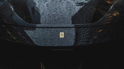Free Close-up of a sleek black car hood adorned with raindrops, reflecting city lights. Stock Photo