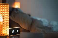 A warm, inviting bedroom with a glowing lamp and digital alarm clock reading 15:11.