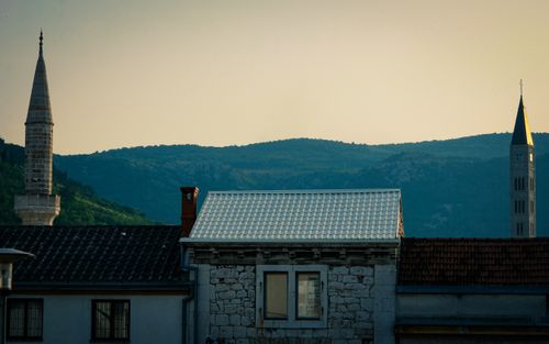 Free Captivating skyline featuring a mosque minaret and church tower against a serene sunset backdrop. Stock Photo
