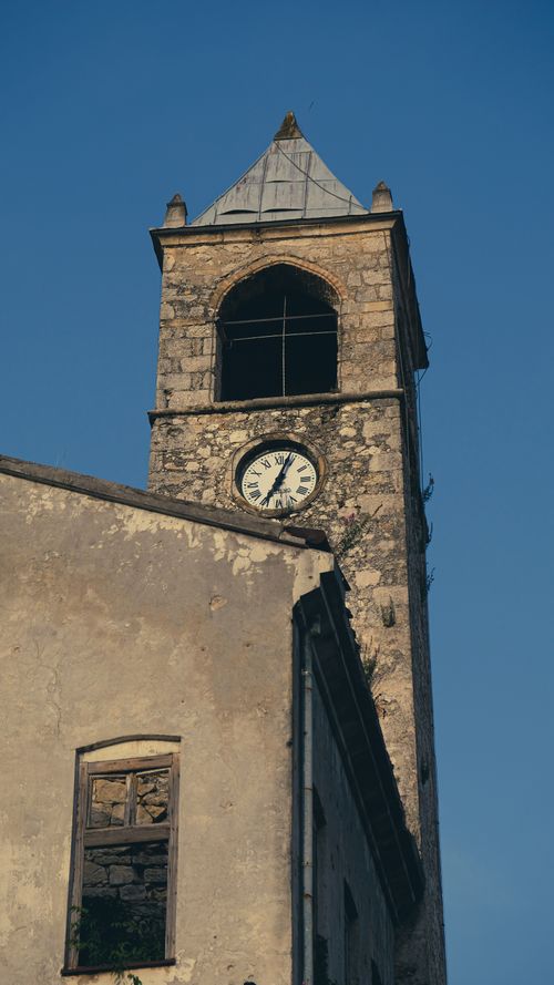 Free Old stone clock tower with visible signs of wear against a clear blue sky. Stock Photo