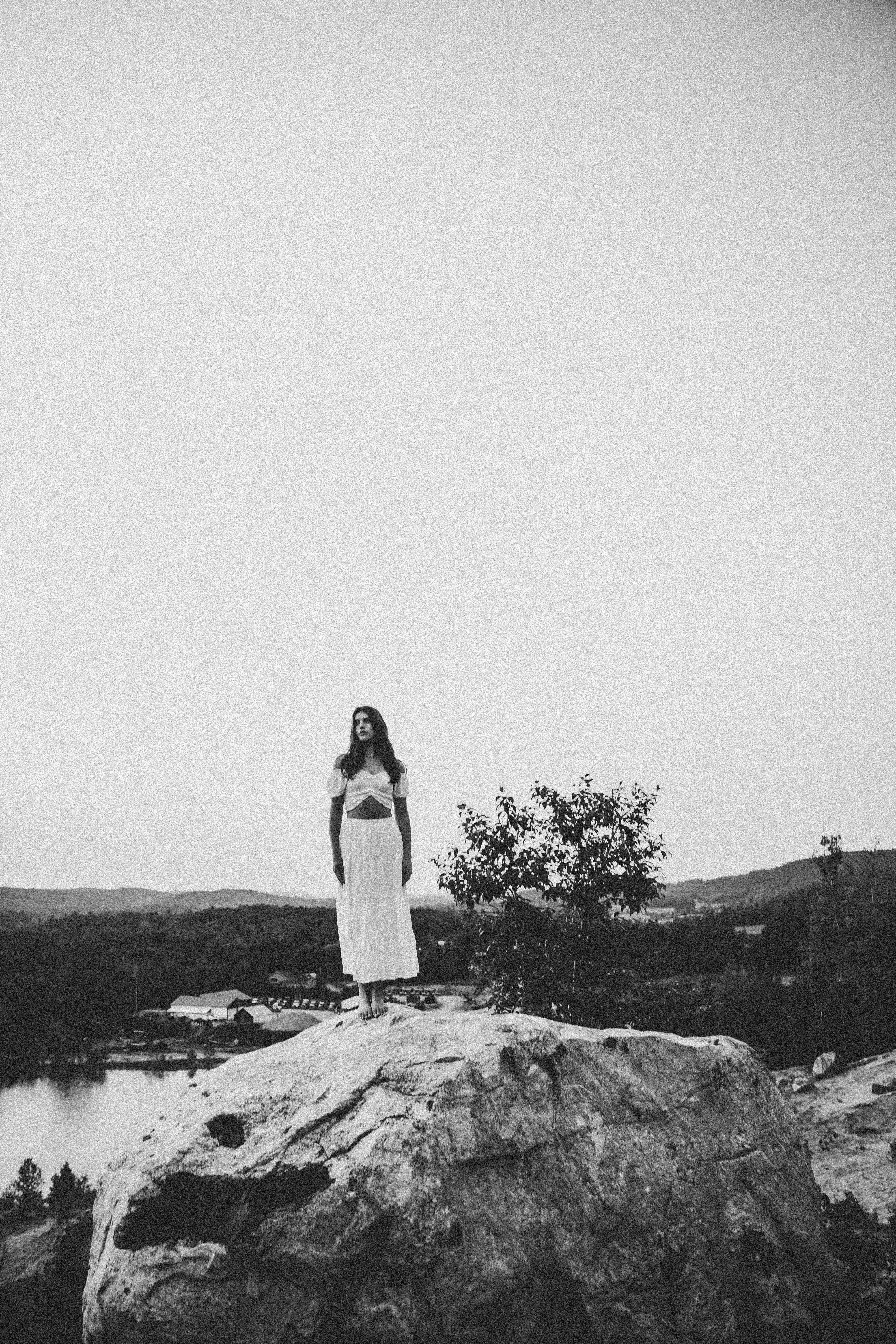Black and white photo of a woman in a dress standing on a rock in Gatineau, QC, Canada.