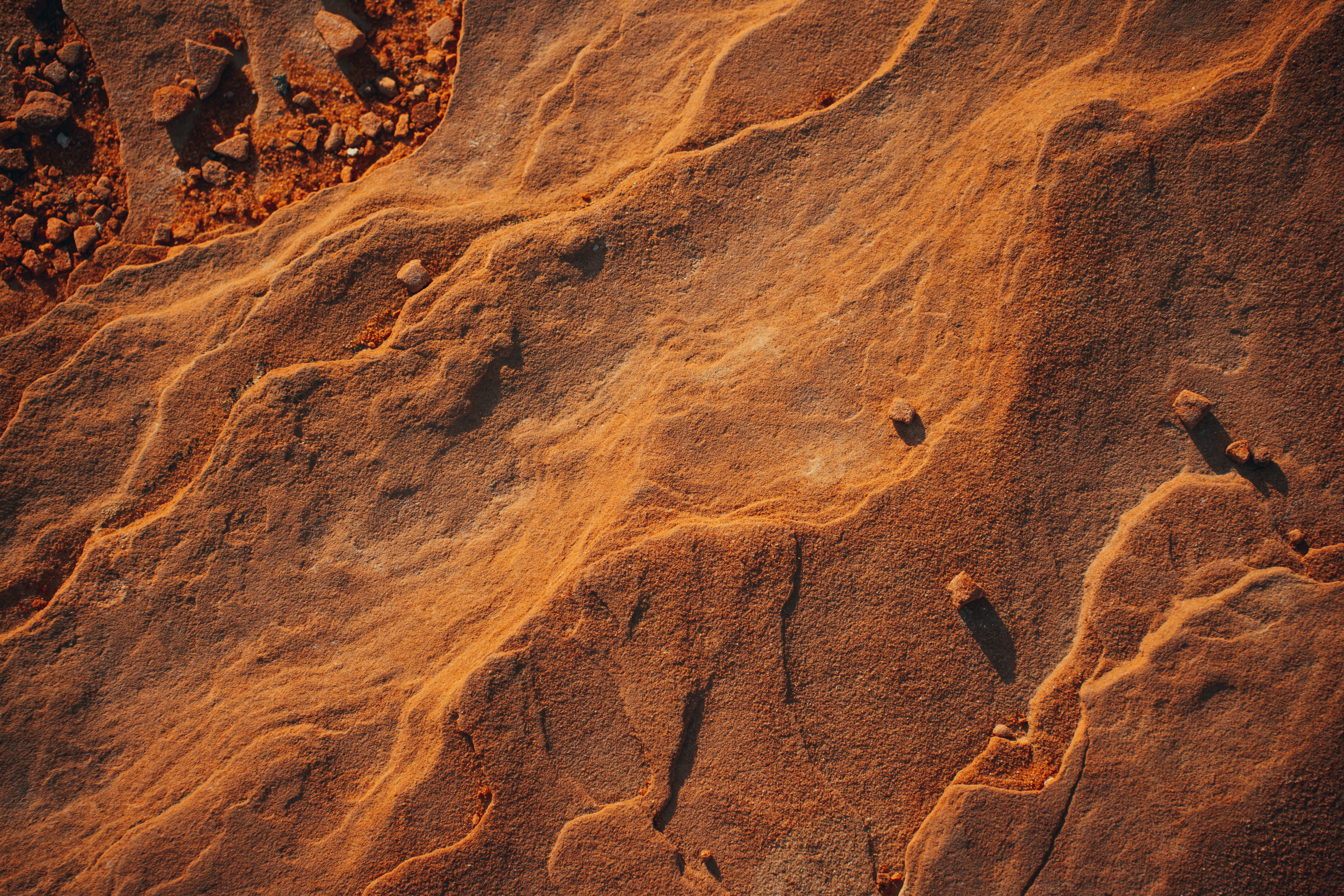Captivating birds-eye view of sunlit desert sand formations showcasing natural textures and patterns.
