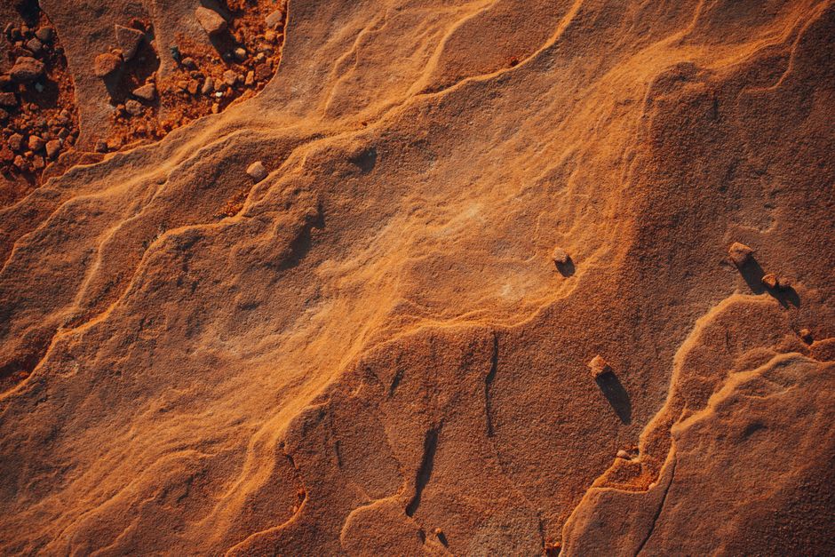 Captivating birds-eye view of sunlit desert sand formations showcasing natural textures and patterns.