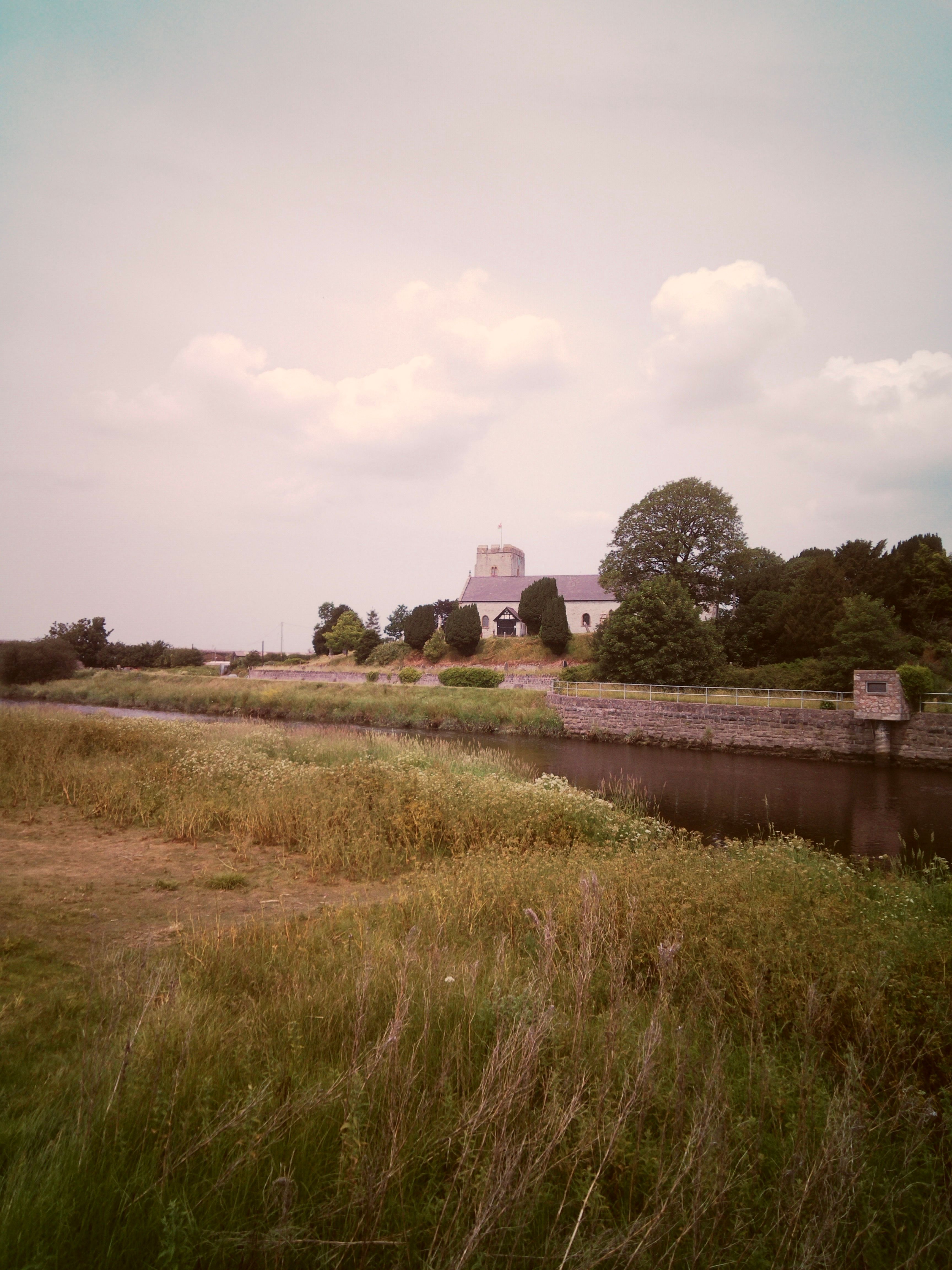 Picturesque summer scene of St. Margaret's Church by a tranquil river in Wales.