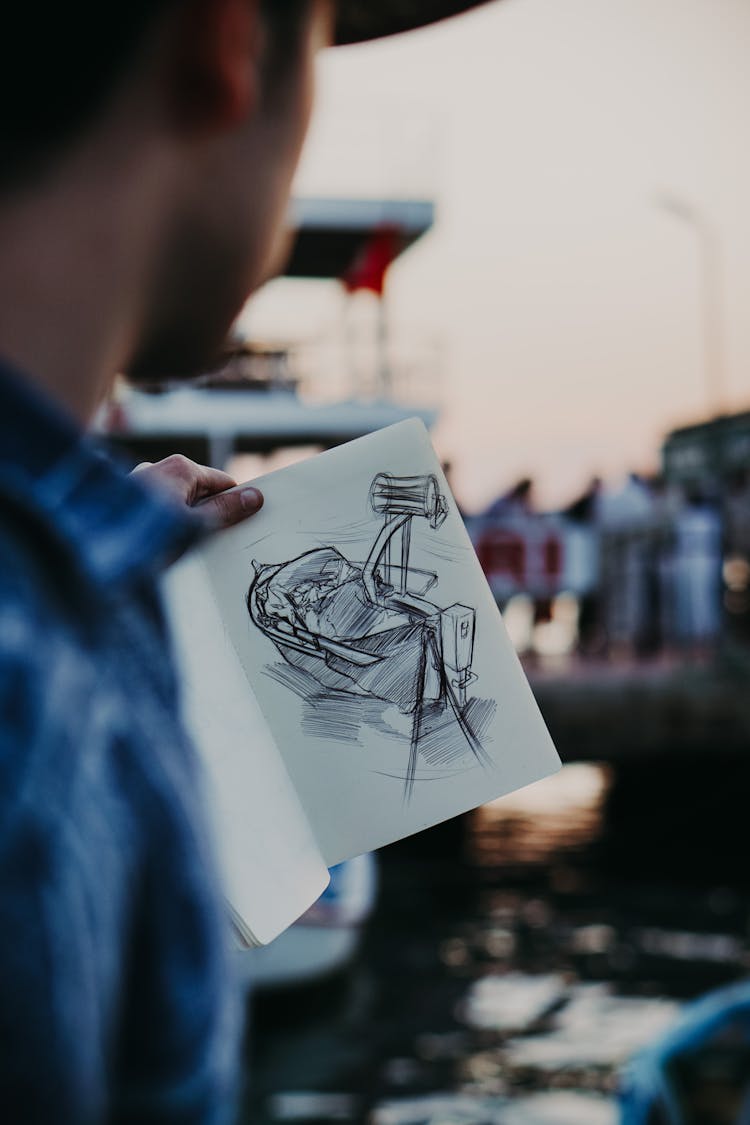 Man Holding Notebook With Drawing