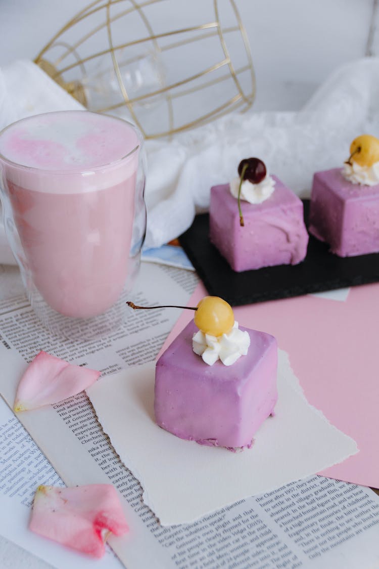 Lavender Colored Glazed Petit Four Cake With Cherry And Pink Fruit Milkshake