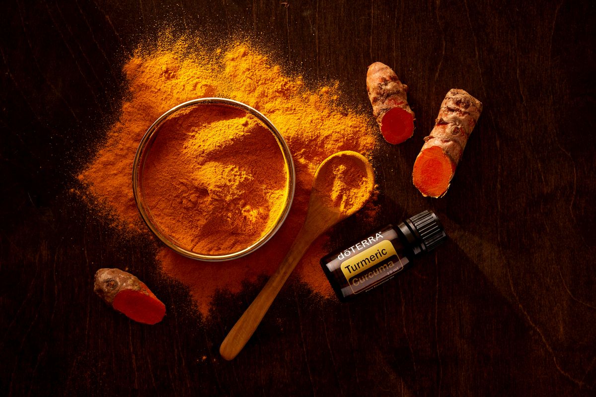 Turmeric powder, curcuma roots, and essential oil on a wooden surface