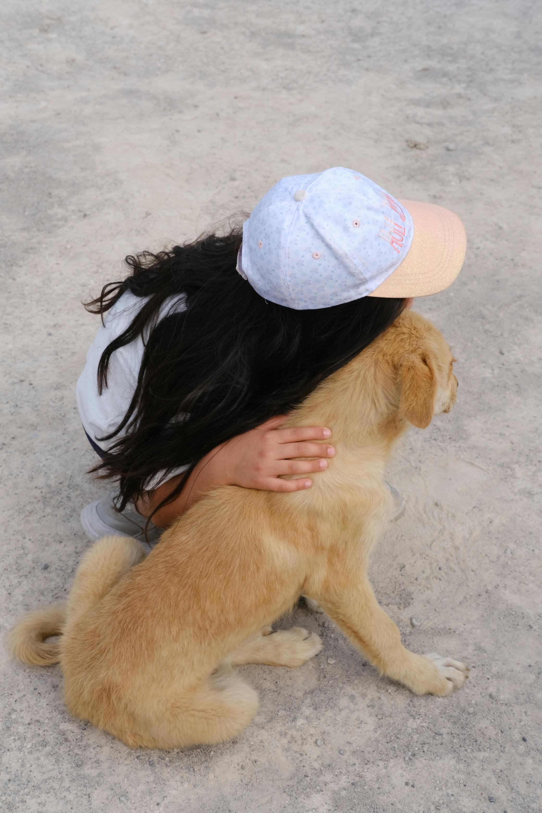 girl in cap hugging dog