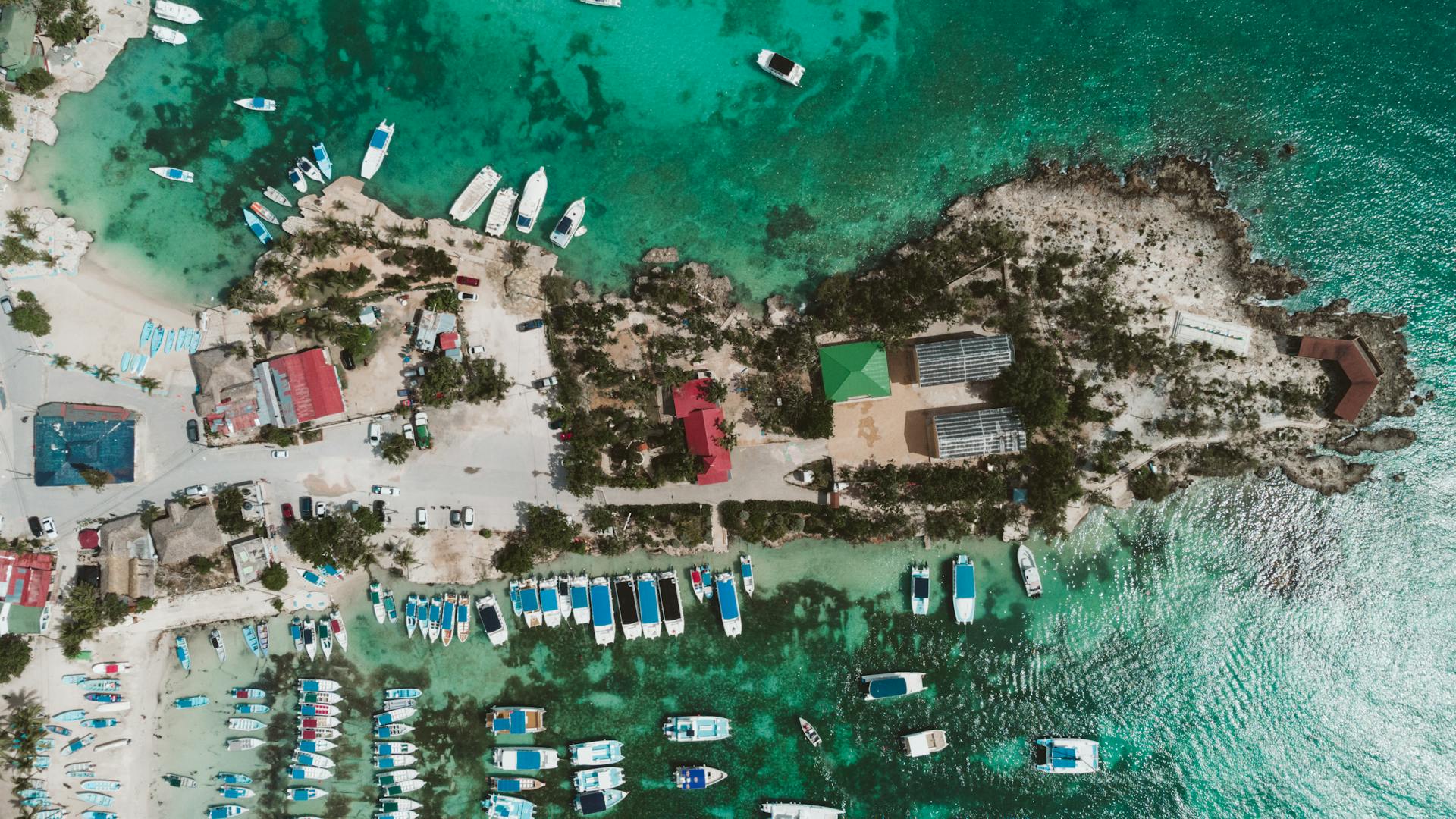 A stunning aerial shot of boats docked along a tropical turquoise shoreline, perfect for travel inspiration.