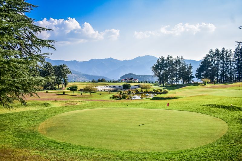 View across a parkland golf course towards a clubhouse on a sunny day