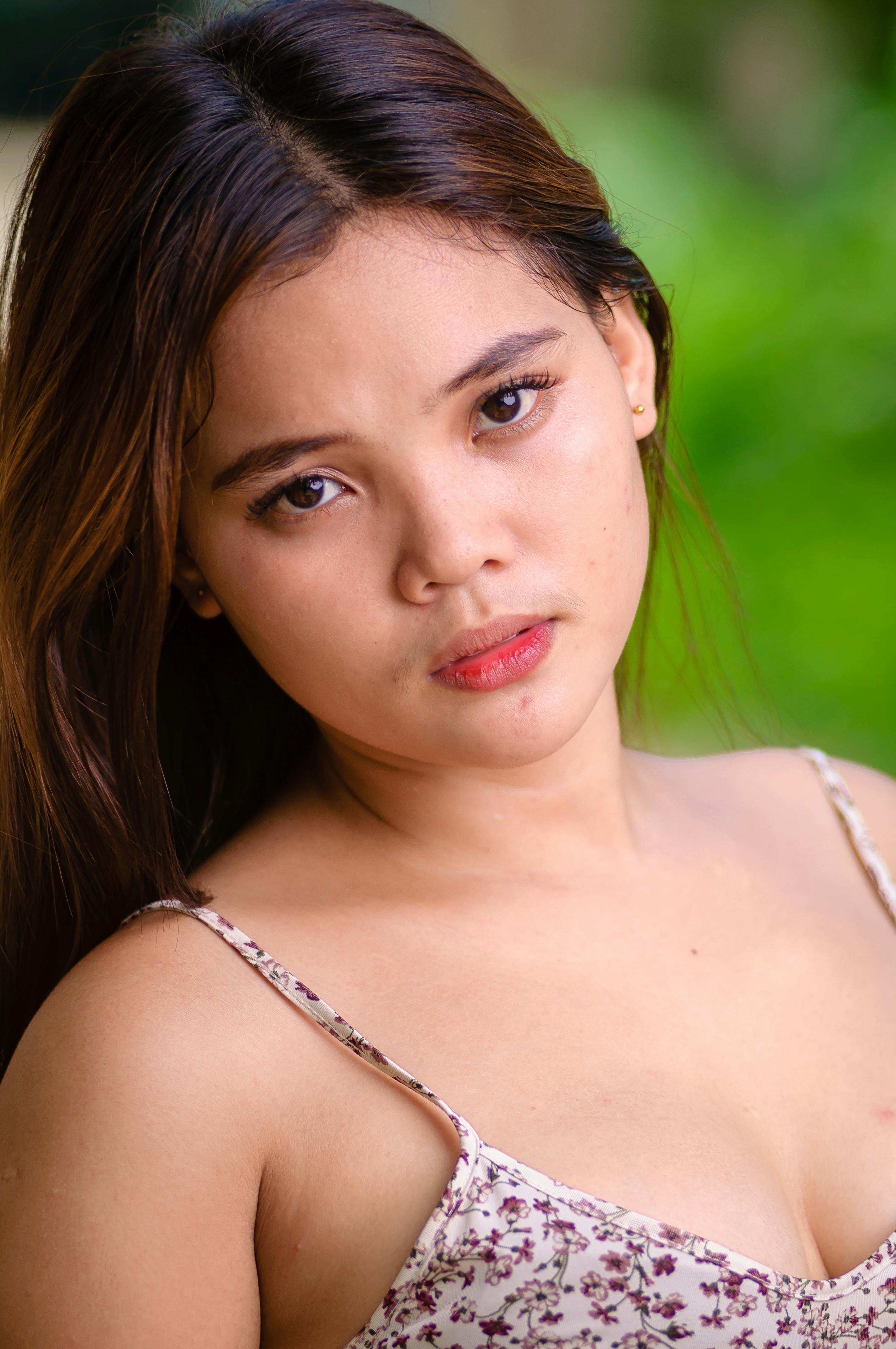 Close-up portrait of a young woman with an outdoor summer background.