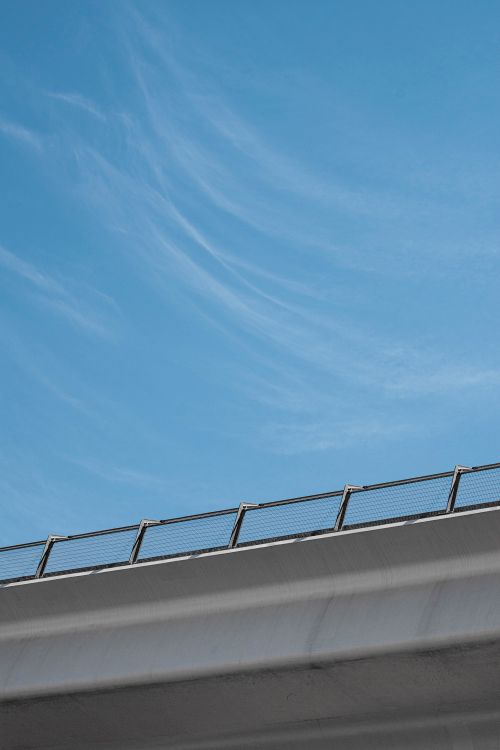 Free A striking low angle view of an urban viaduct against a clear blue sky, highlighting modern architectural elements. Stock Photo