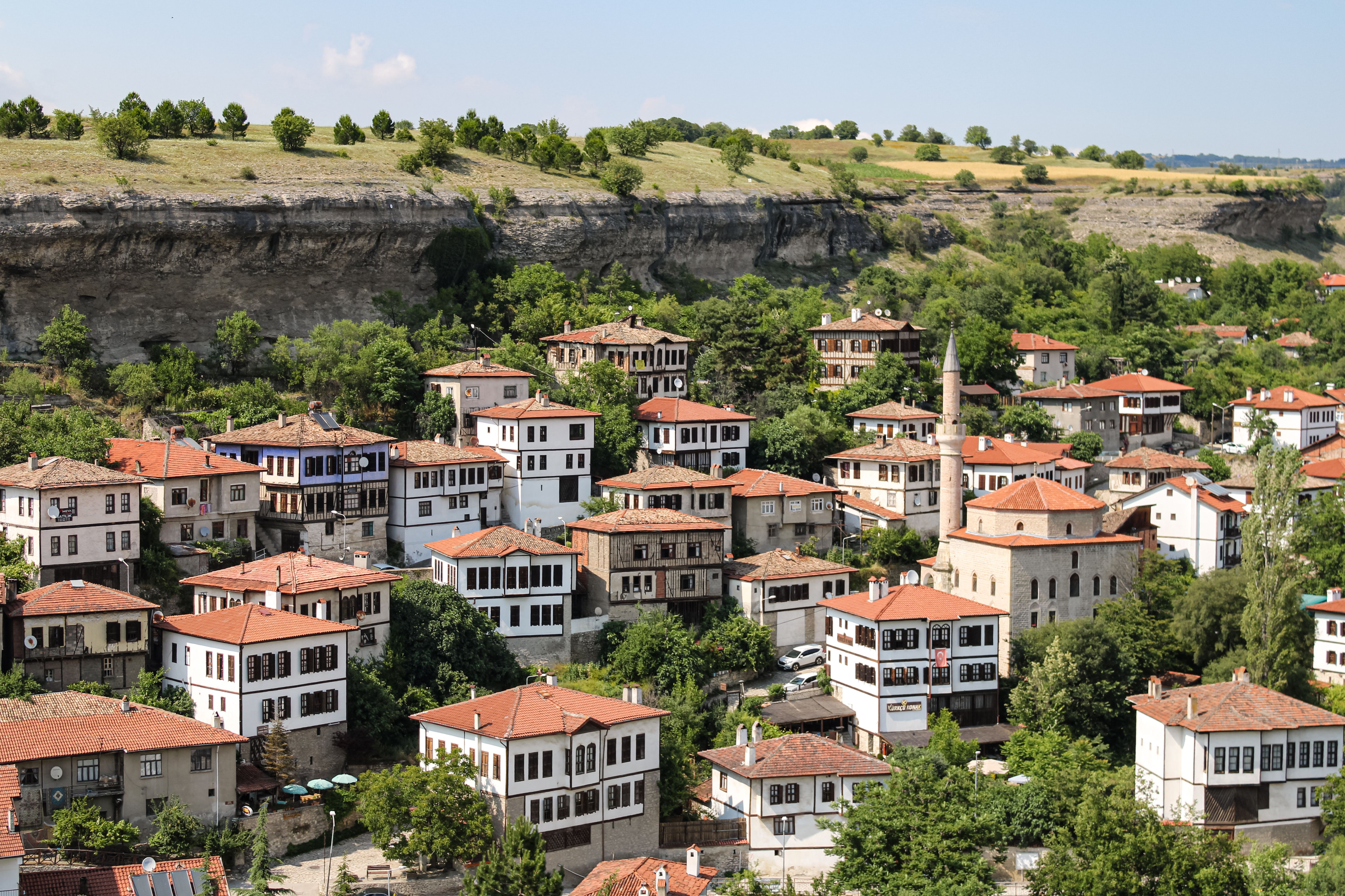Melnik's smallest town at sunset with terracotta rooftops glowing in warm amber light, surrounded by sandstone pyramids