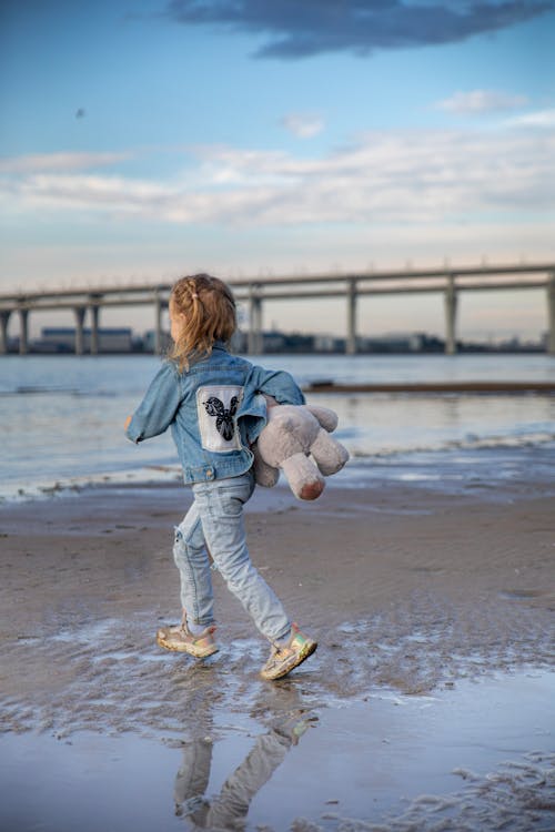 Girl Running with Teddy Toy on Beach