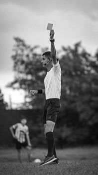 Black and white image of a referee showing a yellow card during a soccer match.