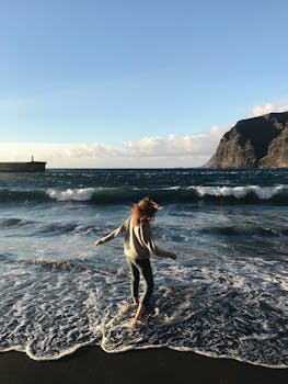 一名女子站在西班牙圣地亚哥德尔泰德海滩的海浪中，捕捉着宁静的海景