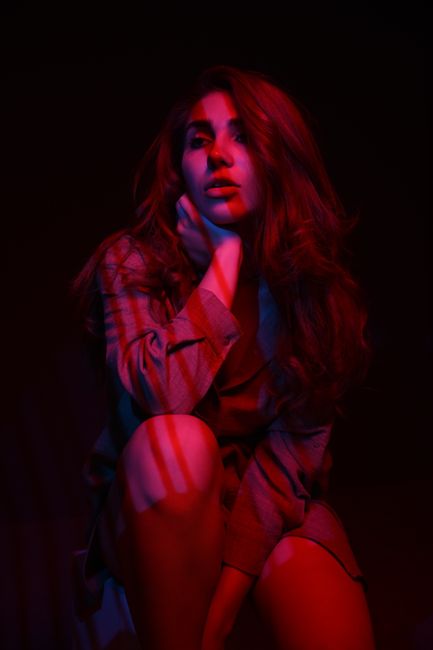 Striking portrait of a woman under red lighting, showcasing dramatic and artistic flair.