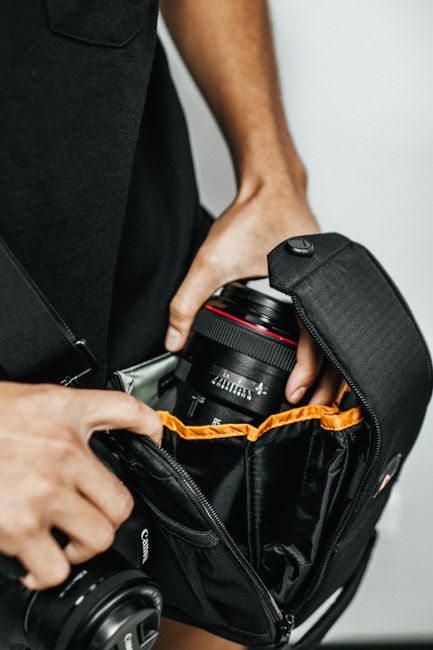 Photographer arranging camera equipment in a bag, ready for travel.