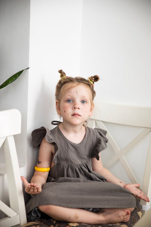 Little Blonde Girl in Gray Dress Sitting on Chair