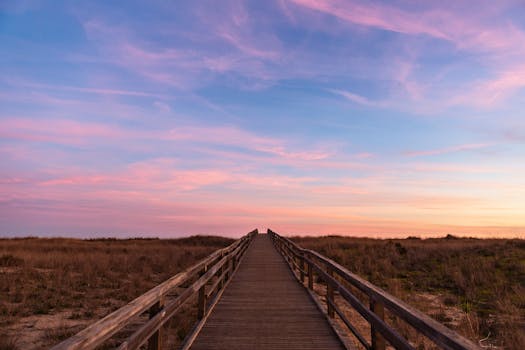 Experience tranquility as the sun sets over a scenic boardwalk in Lagos, Portugal.