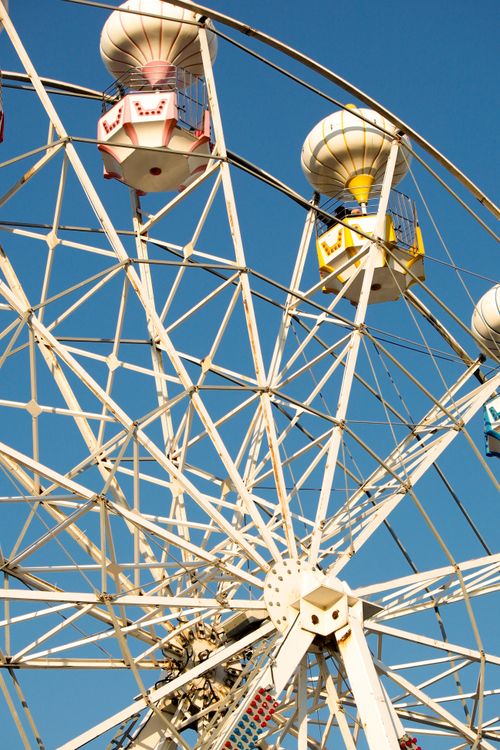 Free A vibrant Ferris wheel with colored gondolas set against a clear blue sky, symbolizing fun and leisure. Stock Photo