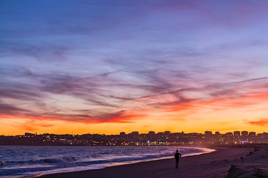 A stunning sunset at Lagos beach, Portugal, with a solitary silhouette and vibrant sky.