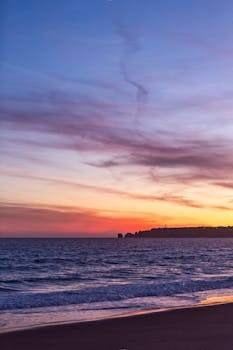 Vibrant sunset at Lagos beach in Portugal with colorful skies and serene waves.