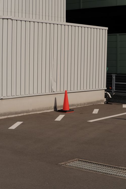 Free Minimalist industrial scene featuring a traffic cone in an urban warehouse parking lot. Stock Photo