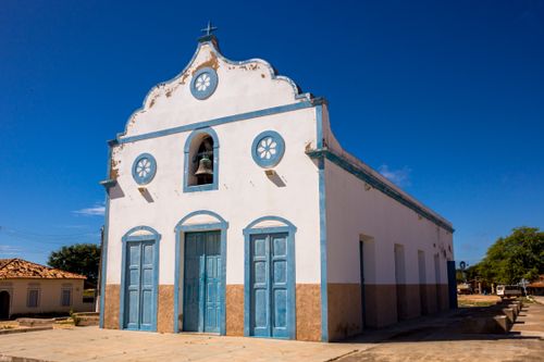 Free A historic white church with blue trim stands under a clear sky in a quaint village. Stock Photo
