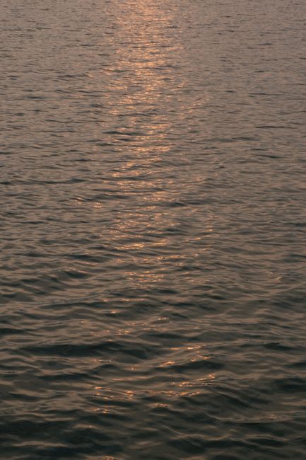Tranquil ocean waters with gentle ripples reflecting the warm hues of a setting sun.
