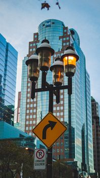 Street lamp and road signs in urban cityscape with modern skyscrapers.