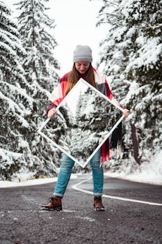 一名妇女拿着镜子，在冬季的道路上捕捉被积雪覆盖的树木