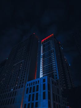 A stunning low angle view of illuminated skyscrapers at night in an urban setting.